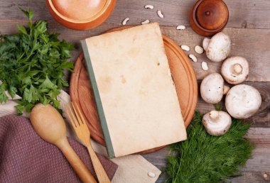 Taze sebzenin karanlık arka planında aşçılık notları için eski bir kitap.