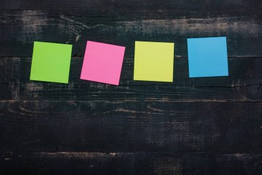 Ahşap arka planda çok renkli kağıt anımsatıcıları.