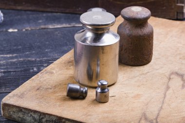 Eski tip demir ağırlıklar, ahşap arka plandaki malları tartmak için.