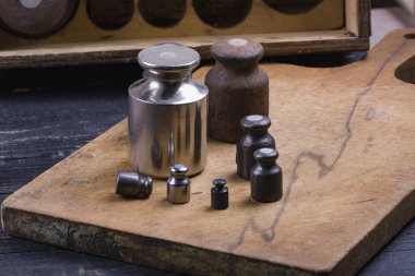 Eski tip demir ağırlıklar, ahşap arka plandaki malları tartmak için.