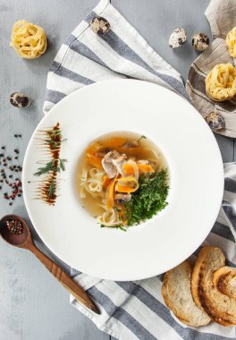 tavuk çorbası erişte ve sebze ile dilim ekmek ve Bıldırcın yumurta bir ahşap gri arka plan üzerinde