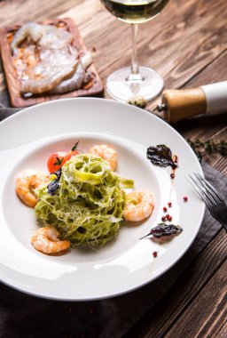 Koyu ahşap backg beyaz bir tabak karides ile yeşil makarna