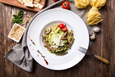 Karanlık wo beyaz bir tabağa et ve parmesan ile yeşil makarna