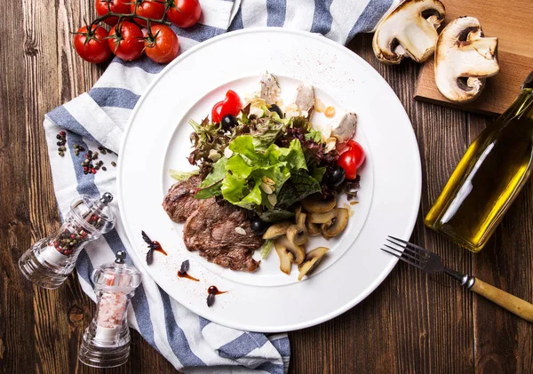 Fleischsalat mit Pilzen auf weißem Teller auf dunklem Holzrücken — Stockfoto