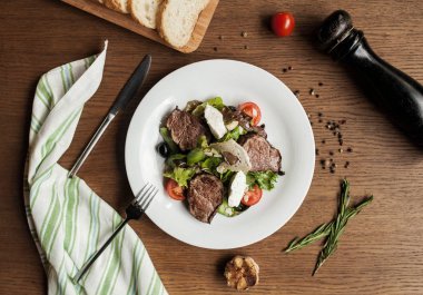 kiraz domates ve ahşap bir masa ekmek tahtasında ile sulu et dilimlerini salata karıştırın