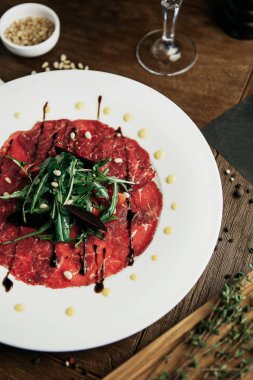 Kırmızı ile beyaz tabakta roka ile Dana carpaccio
