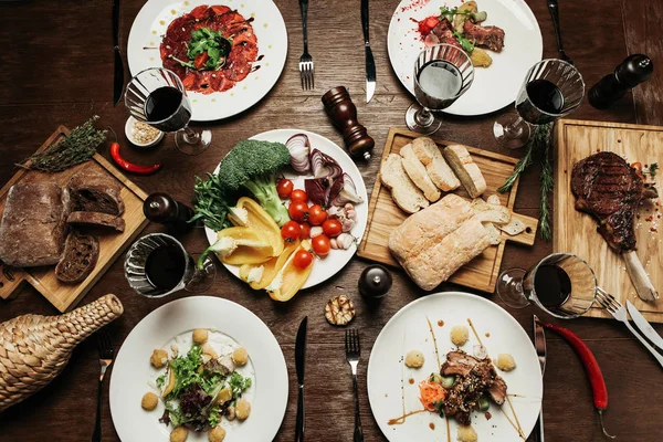 güzel ahşap masa ile farklı yemekler koydu: sığır eti, armut salatası, etli ekmek yönetim kurulu ve sebzeler farklı türde carpaccio ile