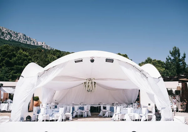 beautifully decorated wedding tent and wedding banquet on a background of mountains and sky