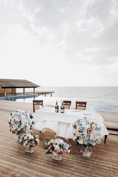 美丽的婚礼桌设置和婚礼装饰与餐具在日落和海背景 — 图库照片