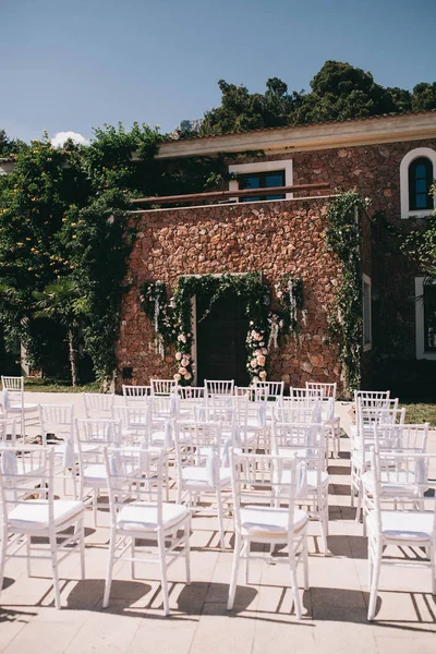 a beautifully decorated wedding ceremony, a floral wedding arch and chairs