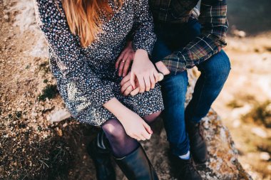 denizin üzerinde bir kayaya oturan genç şık çift