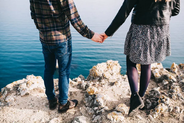 年轻的情侣走着 手牵着石头 美丽的海景和山脉 — 图库照片