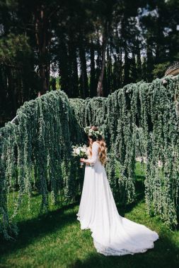 Kafasındaki ile güneşli havalarda yeşil çimenlerin üzerinde bir düğün buket çiçek çelenk içinde şık gelin