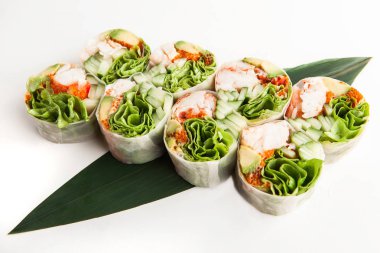 parlak bahar yengeç eti, avokado, salatalık ruloları ve beyaz bir arka plan bambu yaprağına Yeşiller