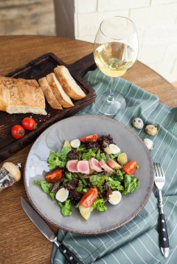 dilim ekmek, bıldırcın yumurtası ve bir bardak beyaz şarap ahşap bir masa üzerinde ton balığı ile klasik salata salata