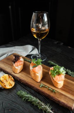 Üç bruschettes peynir ve bir bardak beyaz şarap ile ahşap bir gemide taze somon ile