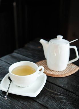 Beyaz su ısıtıcısı ve koyu ahşap arka plan üzerinde bir daire üzerinde çay