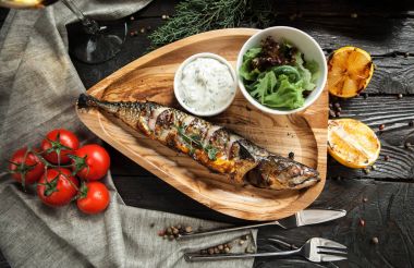 Koyu ahşap arka plan üzerinde beyaz şarap ile ahşap bir plaka üzerinde limonlu güzel ızgara balık