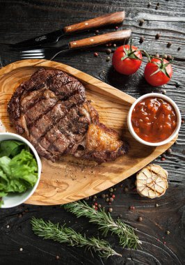 Domates soslu dana biftek ve koyu ahşap arka plan üzerinde kırmızı şarap ile bir salata güzel bir hizmet