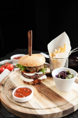 Burger buğday ekmek, patates kızartması ve salata ahşap oyun tahtası