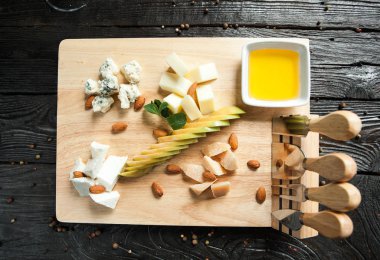 Peynir tabağı ile fındık, elma ve bir bardak beyaz şarap ile ahşap bir gemide tatlım