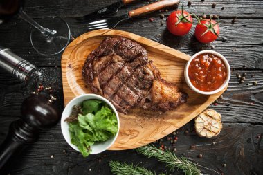 Domates soslu dana biftek ve koyu ahşap arka plan üzerinde kırmızı şarap ile bir salata güzel bir hizmet