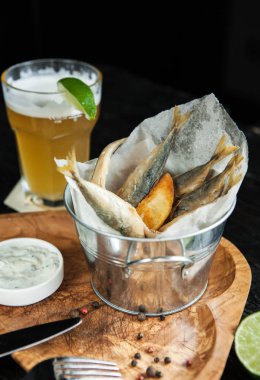 snack için bira - kızarmış patates ve sosu bir bardak hafif bira ile ahşap plaka ile küçük balık