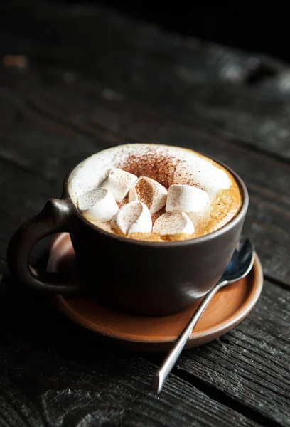 cup of coffee with marshmallow on a dark wooden background