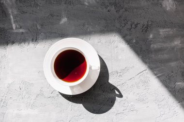 Beyaz bir daire gri beton zemin üzerine siyah çay fincan