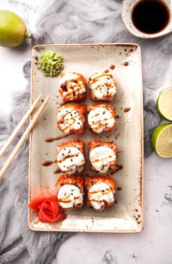 Yemek çubukları, soya sosu ve kireç ile beyaz bir beton zemin üzerine Japon suşi rulo