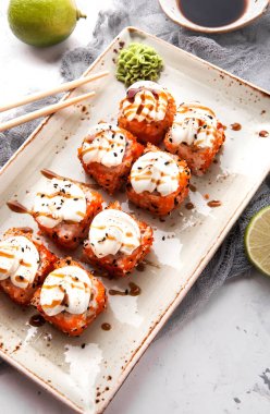 Yemek çubukları, soya sosu ve kireç ile beyaz bir beton zemin üzerine Japon suşi rulo