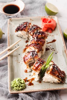 Yemek çubukları, soya sosu ve kireç ile beyaz bir beton zemin üzerine Japon suşi rulo