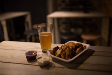 Bira, tavuk kanadı ve sosu bir tabloda pub