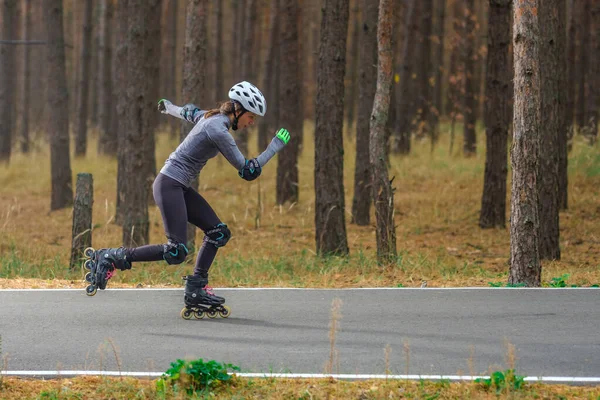 Roller skating sports girl in a helmet outdoors.
