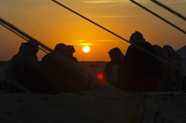 Mannen rond een vuur plaats in de woestijn bij zonsopgang — Stockfoto