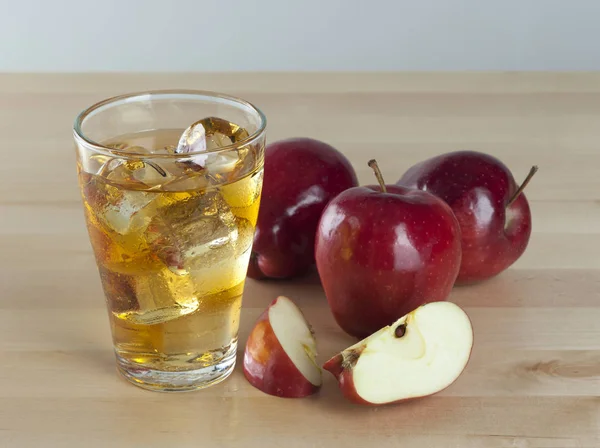 Un verre de jus de pomme frais froid avec de la glace à côté des pommes — Photo