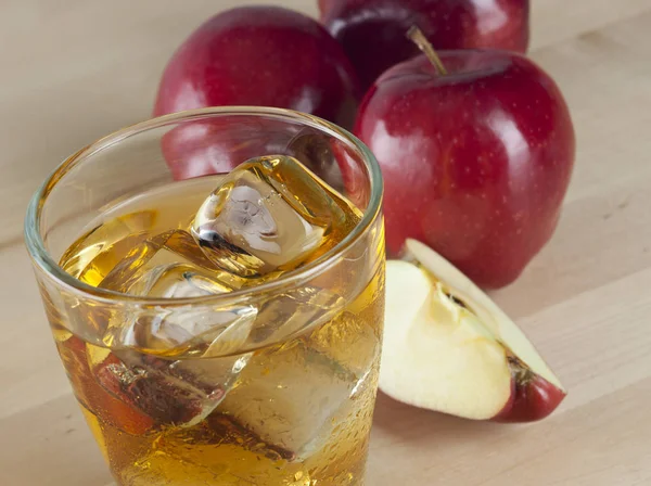 Un vaso de zumo de manzana fría fresca con hielo junto a las manzanas —  Fotos de Stock