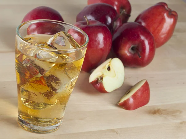 Un vaso de zumo de manzana fría fresca con hielo junto a las manzanas —  Fotos de Stock