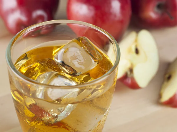 Un verre de jus de pomme frais froid avec de la glace à côté des pommes — Photo