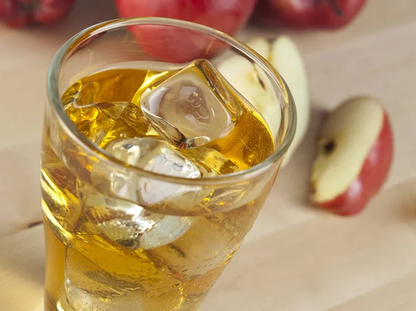 Un vaso de zumo de manzana fría fresca con hielo junto a las manzanas —  Fotos de Stock