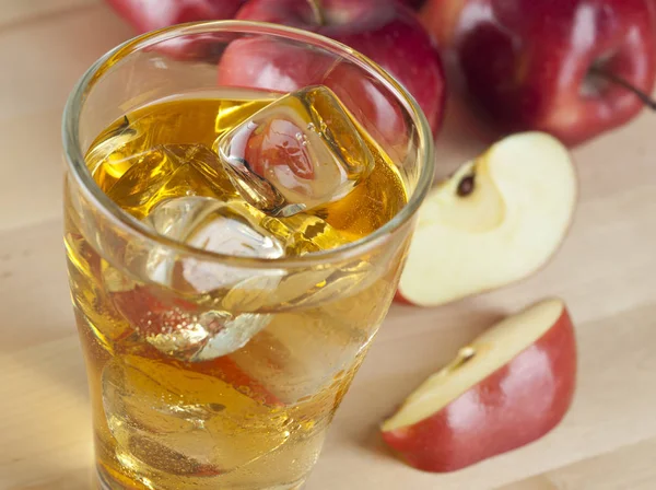 Un vaso de zumo de manzana fría fresca con hielo junto a las manzanas en un Wo —  Fotos de Stock