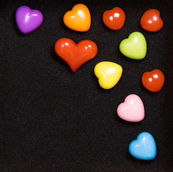 Colorful hearts on a black background with a place for the inscription — Stock Photo, Image