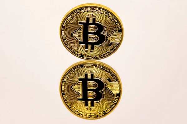 Representación conceptual de un bitcoin de oro sobre una superficie de espejo blanco . — Foto de Stock