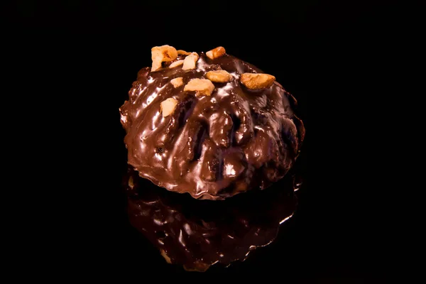 Pastel de chocolate en una superficie de espejo negro espolvoreada con nuez, caramelo de chokolate oscuro — Foto de Stock