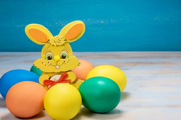 Paskalya egge mavi rustik ahşap arka plan üzerinde daire içinde renk tavşan — Stok fotoğraf