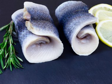 Frenk soğanlı ringa dürümü ve koyu arkaplanda servis edilen limon.