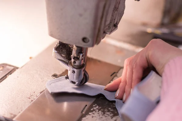 Hands of seamstress, fabric and sewing machine, close-up. Episode of work in the studio - the process of tailoring, detail close-up - the machine, thread, fabric, needle.