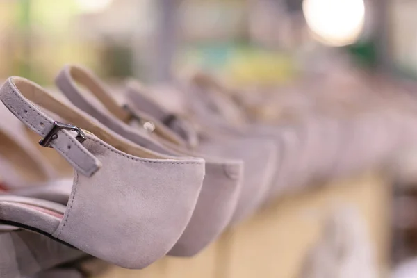 worker making white leather shoe on production line conveyor in footwear factory