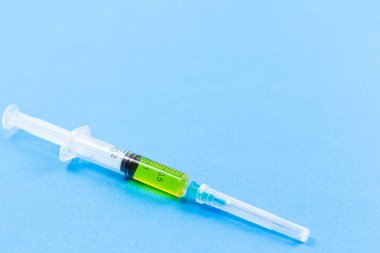 Mavi zemin üzerinde yeşil bir şırınga, Covid-19l enjeksiyon konsepti kopyacı