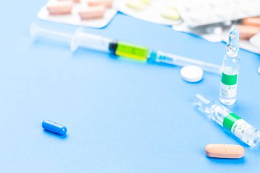 Aşı için şırınga ve mavi arka planda haplar. Tıbbi konular. İlaçlar. Coronavirus. Virüsten kimlik tespiti. Mesaj için yer. Boşluğu kopyala.